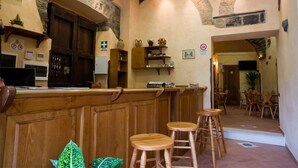 A bar area with wooden stools, a counter, and a stone wall. - La Perla del Sannio (Sant'Agata de'Goti)