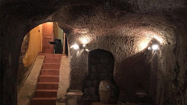 A stone-walled tunnel with a wooden staircase leading to a door. There are two wall-mounted lights and a stone bench. - La Perla del Sannio (Sant'Agata de'Goti)