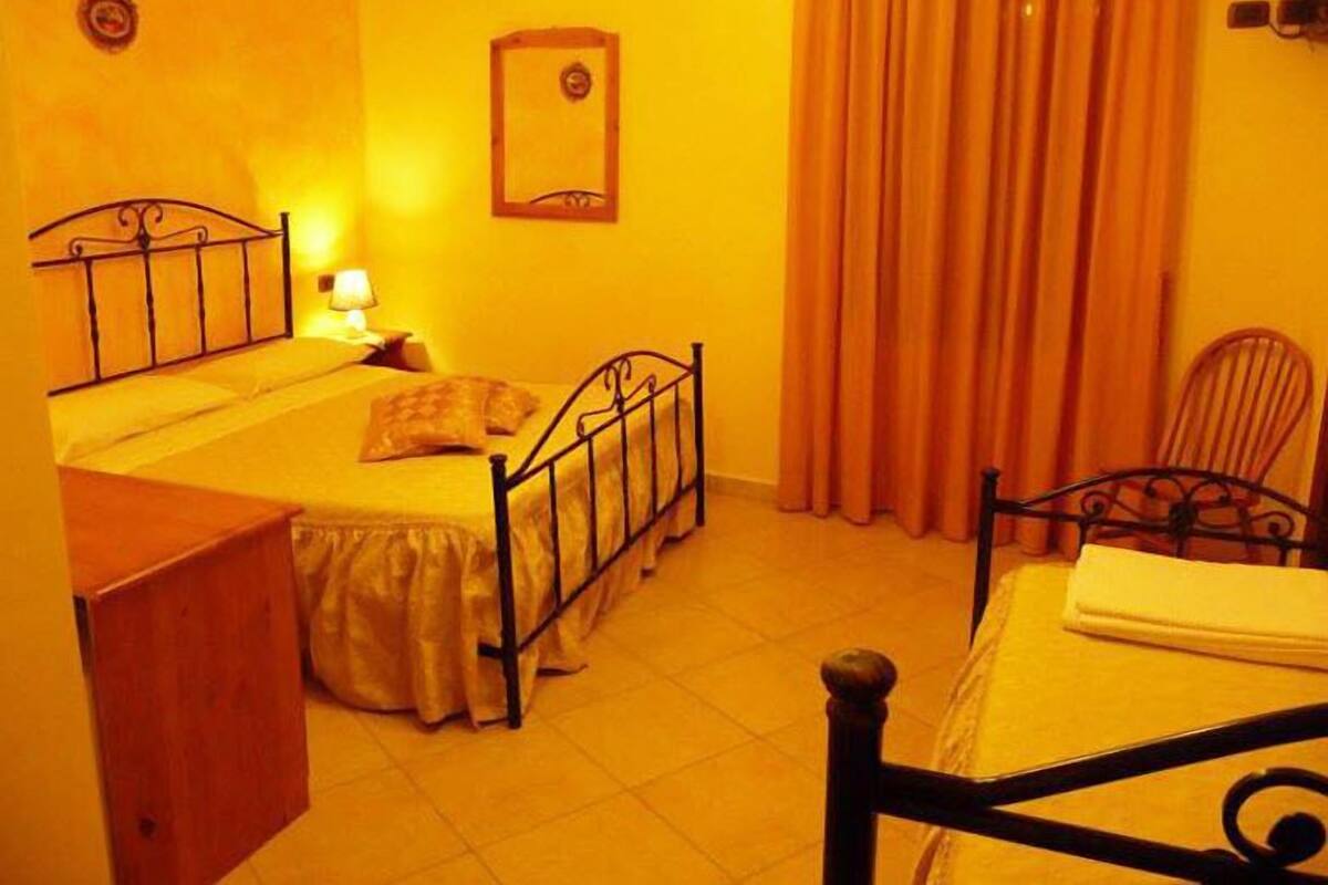 Un dormitorio pequeño y acogedor con una cama individual, una mesita de noche, una silla y un armario de madera.