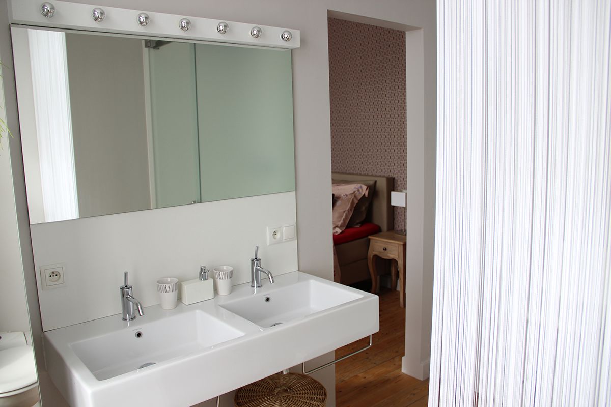 Une salle de bain avec un grand miroir, deux lavabos et un plancher en bois.