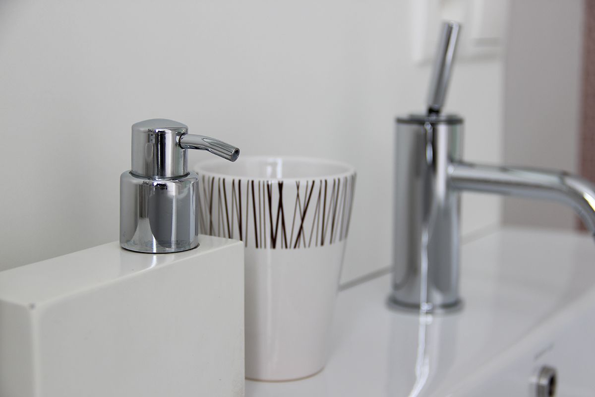 A bathroom with a modern faucet, a white sink, and a decorative cup with vertical lines.