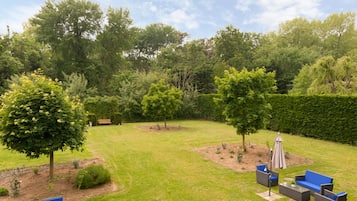 A well-maintained garden with a lawn, a bench, and outdoor furniture.