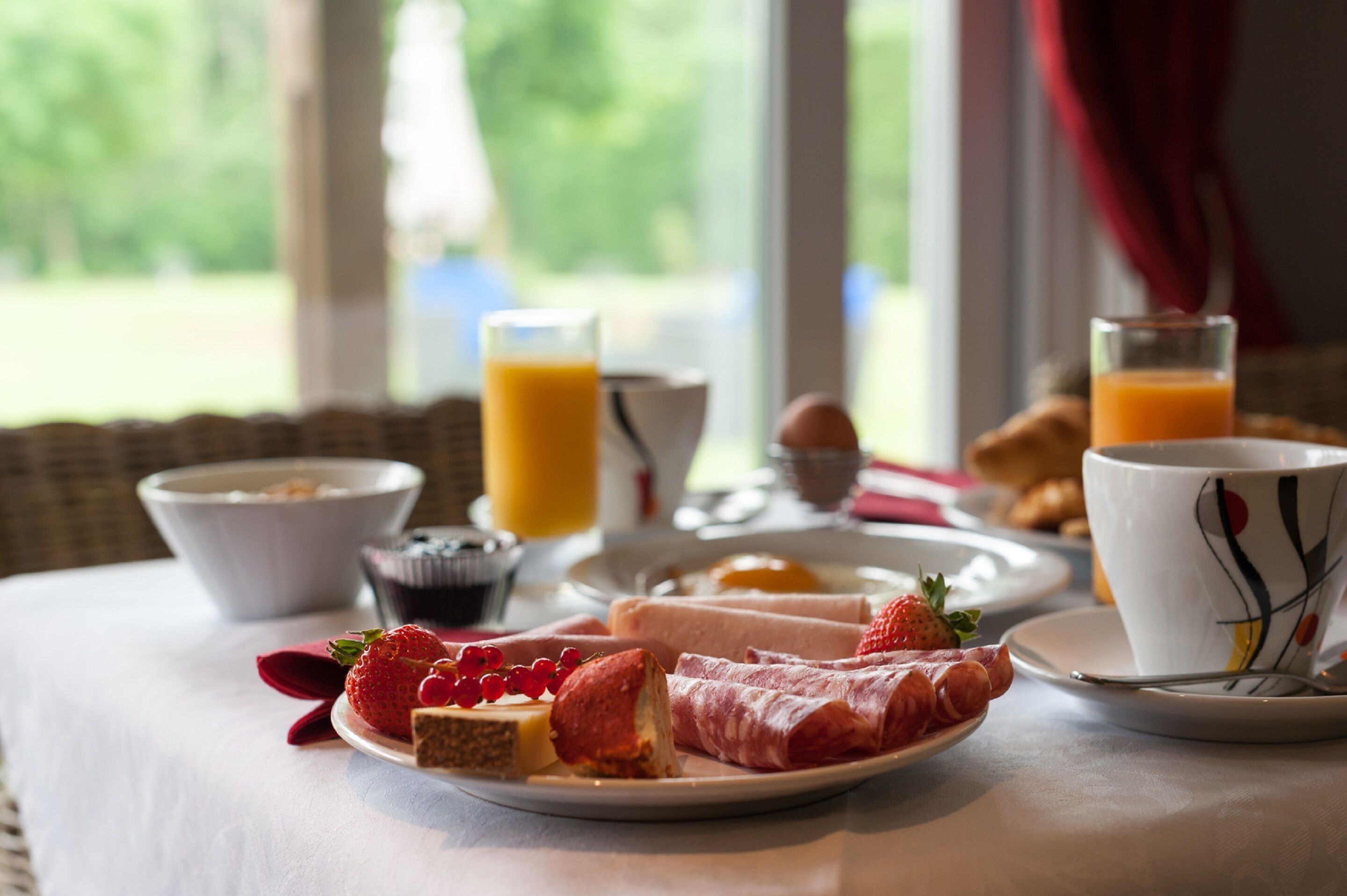 Una escena de desayuno con un plato de comida, un bol y un vaso de jugo de naranja.
