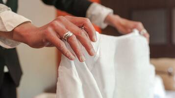 A person holding a white garment, likely a shirt, with a ring on their finger.