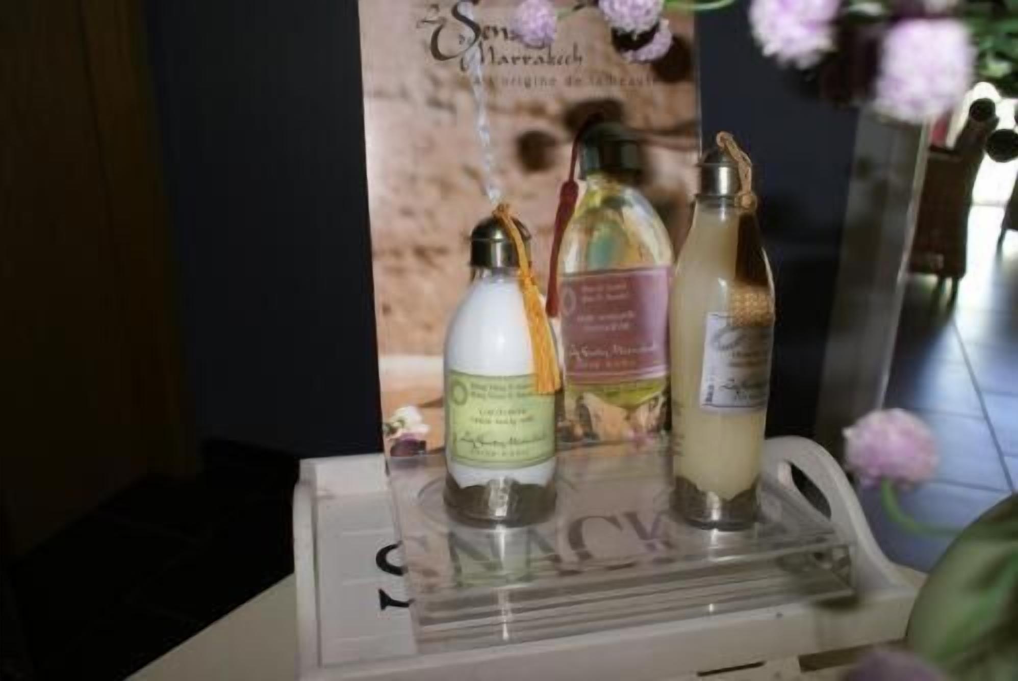 Tres botellas de líquido sobre un expositor, con un fondo floral.