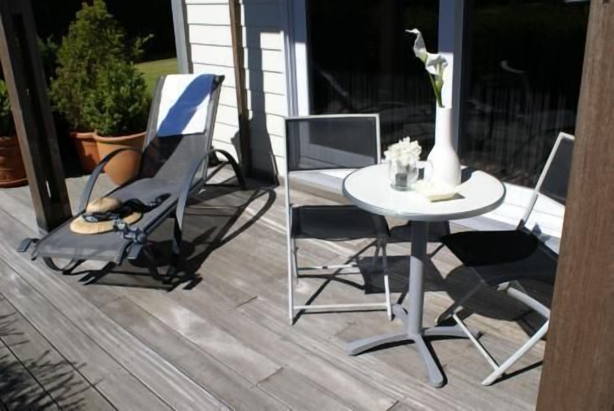 Een overdekt terras met een ronde tafel en twee stoelen.