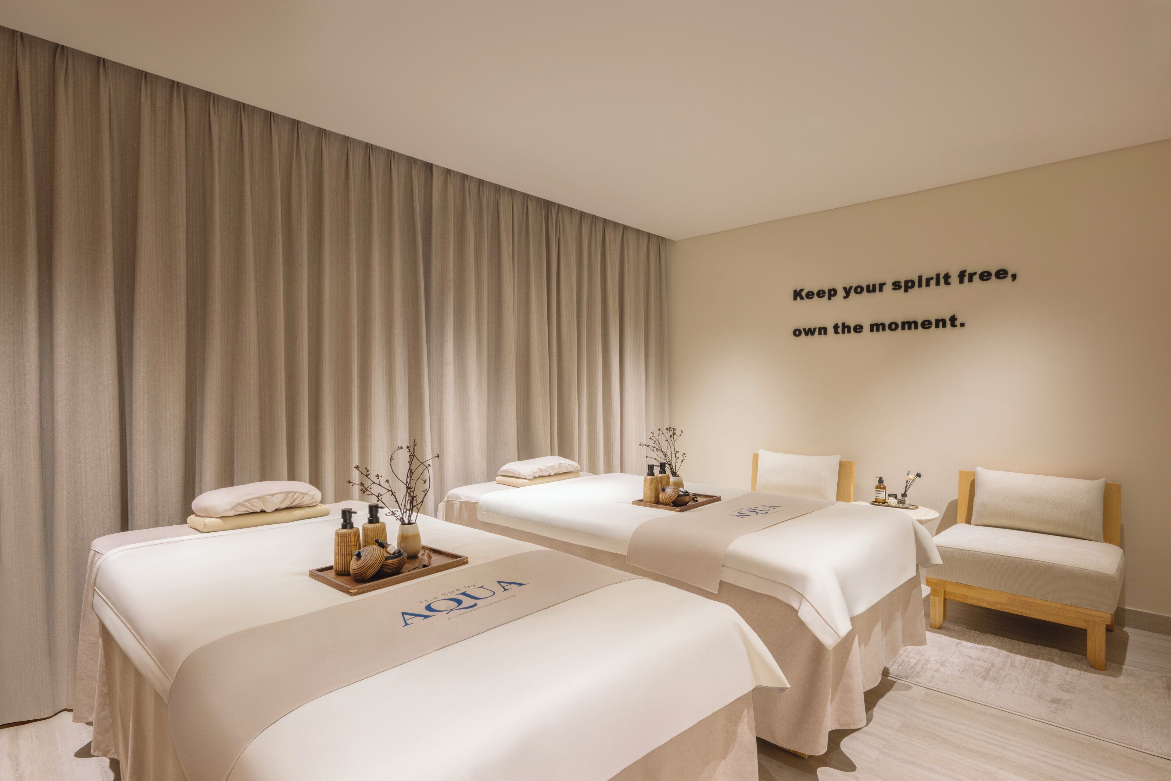 Un cuarto de spa con dos camas, un banco y una pared con una cita motivacional.
