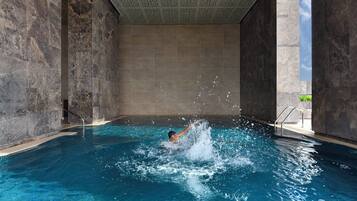 Una piscina al aire libre, sombrillas, sillones reclinables de piscina