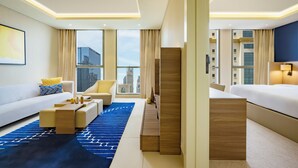 Una habitación de hotel moderna con sofá, sillón, escritorio y cama.