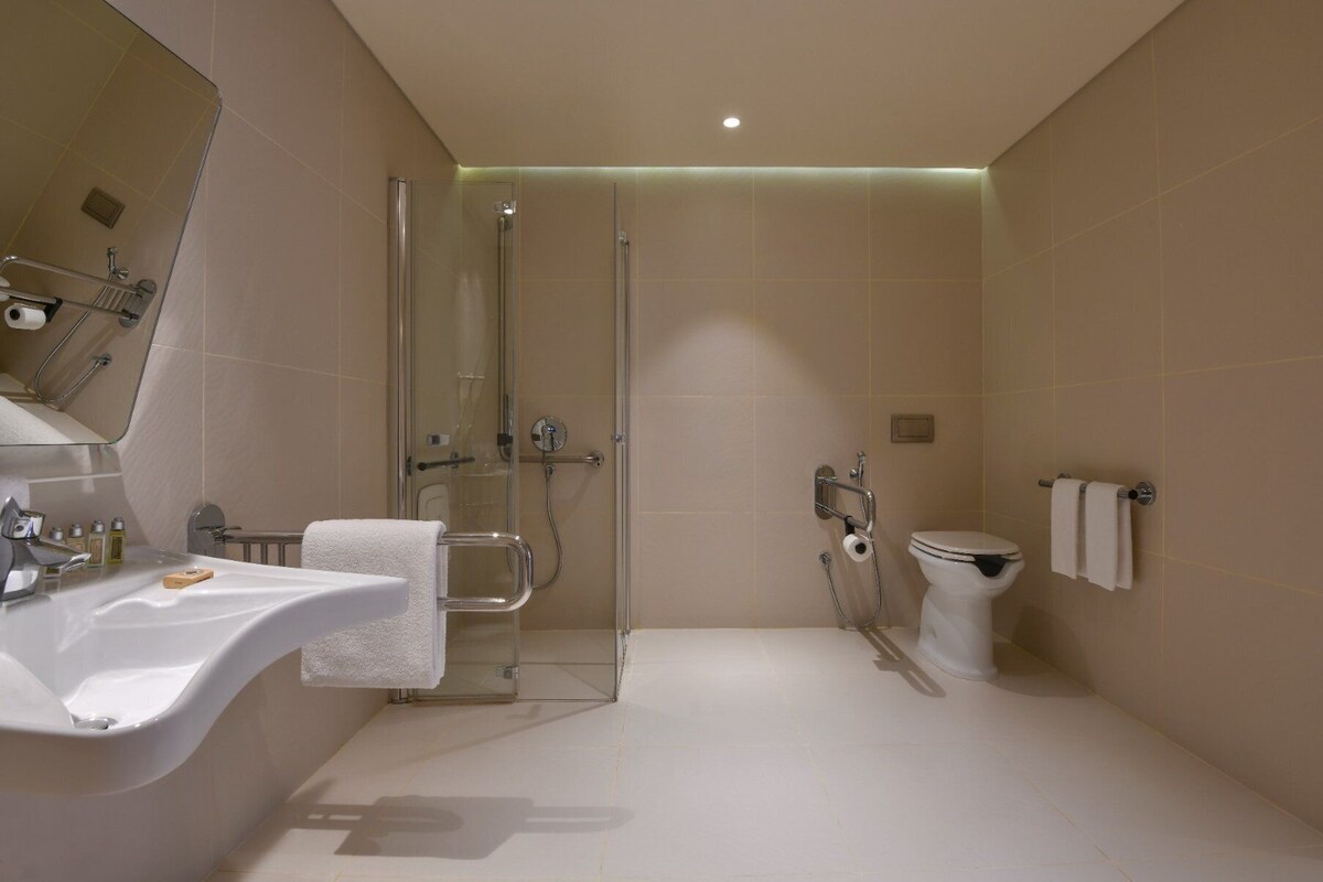 A modern bathroom with a bathtub, toilet, and shower.