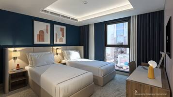 Habitación de hotel con dos camas, un escritorio, una silla, un ventanal con vista a la ciudad y obras de arte en la pared.