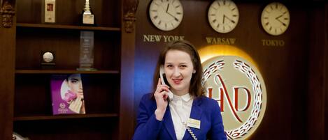 A reception desk with clocks displaying New York, Warsaw, and Tokyo times.