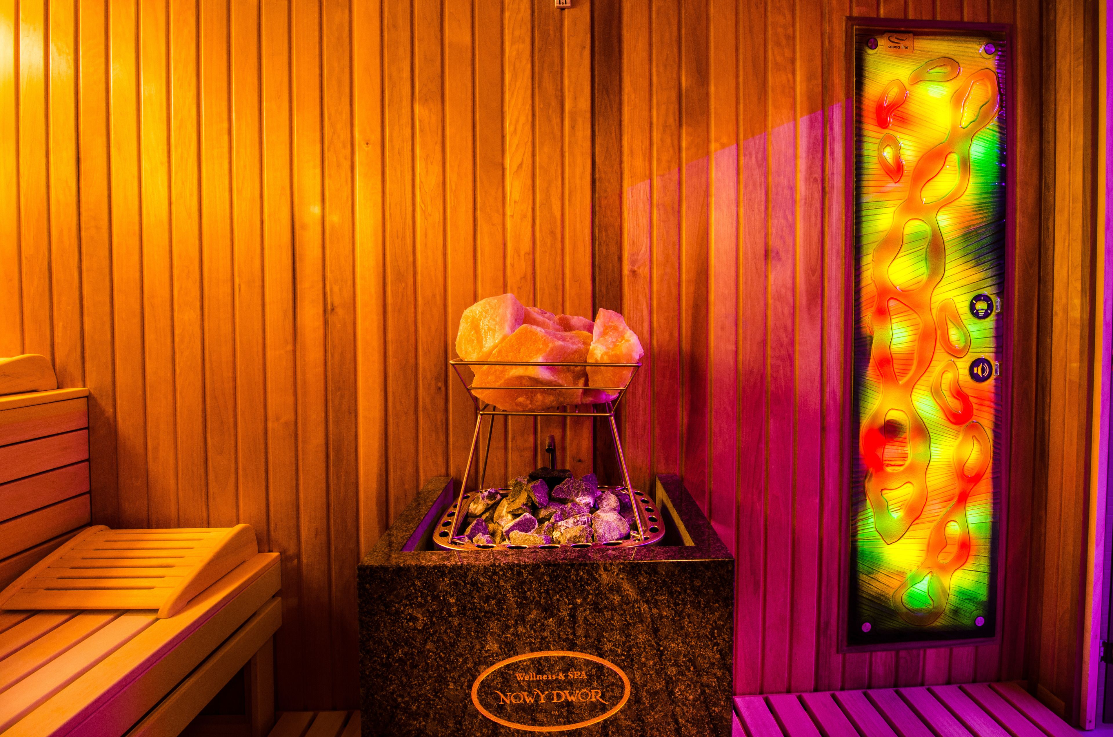 A sauna with wooden walls, a bench, and a glass door with a colorful pattern.