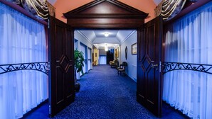 A hallway with a blue carpet, wooden doors, and a ceiling light.