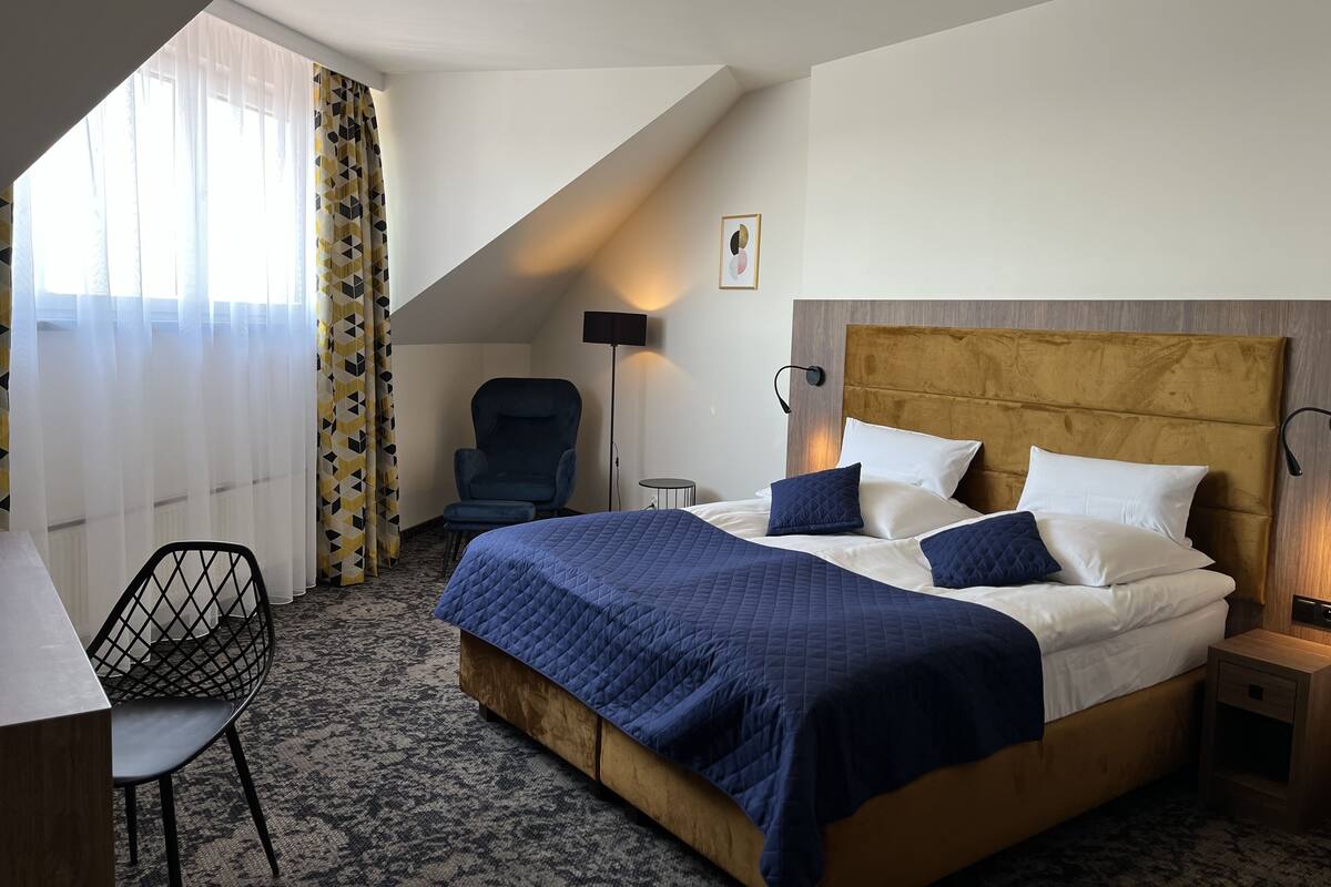 Una habitación de hotel con una cama grande, un escritorio, una silla y una ventana con cortinas.