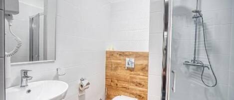 Une salle de bain moderne avec un lavabo blanc, un meuble-lavabo en bois, des toilettes et une douche à parois de verre.