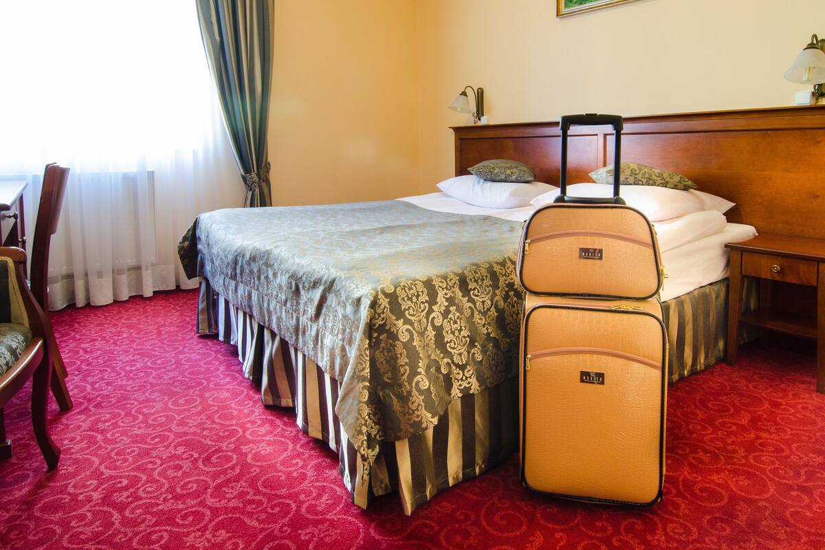 Una habitación de hotel con una cama, un escritorio, una silla y una maleta.