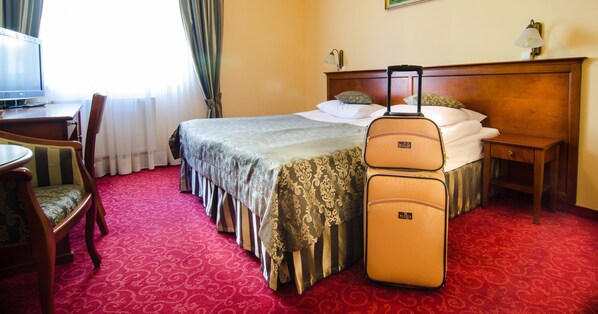 Una habitación de hotel con una cama, un escritorio, una silla y una maleta.