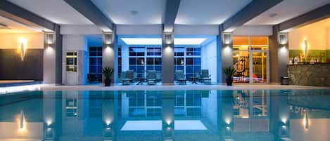 Una piscina techada, sillones reclinables de piscina