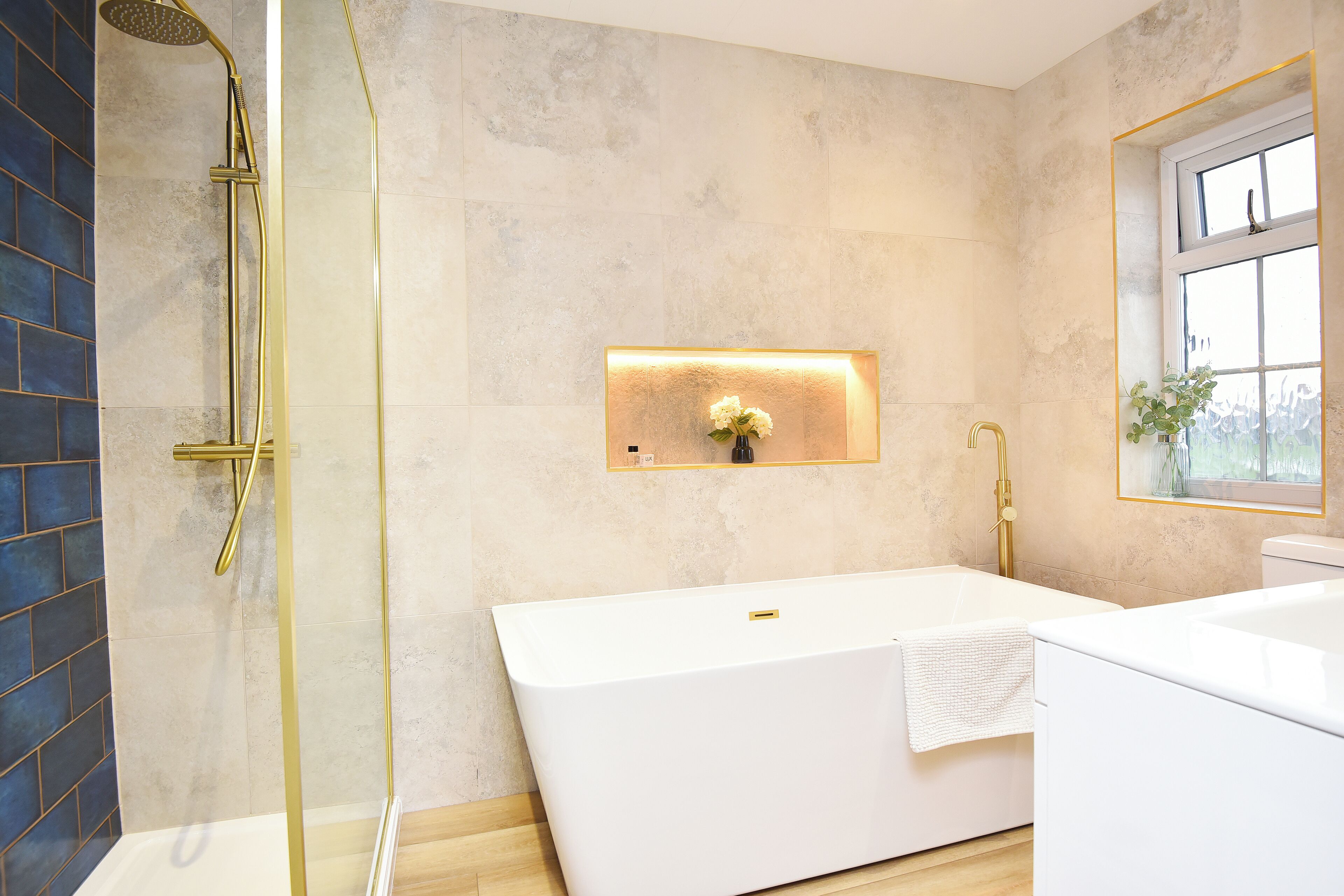 A modern bathroom with a freestanding bathtub, a glass-enclosed shower, and a wall-mounted light fixture.