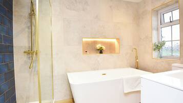 A modern bathroom with a freestanding bathtub, a glass-enclosed shower, and a wall-mounted light fixture.