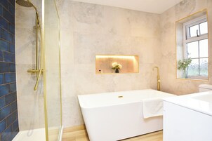 A modern bathroom with a freestanding bathtub, a glass-enclosed shower, and a wall-mounted light fixture.