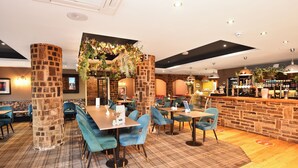 Un restaurante con un pilar de ladrillo, sillas azules y una zona de bar.