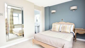 A bedroom with a bed, a mirror, a nightstand, and a wall-mounted light fixture.