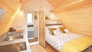 Un interior de madera con una cama, un lavamanos y una pequeña cocina.