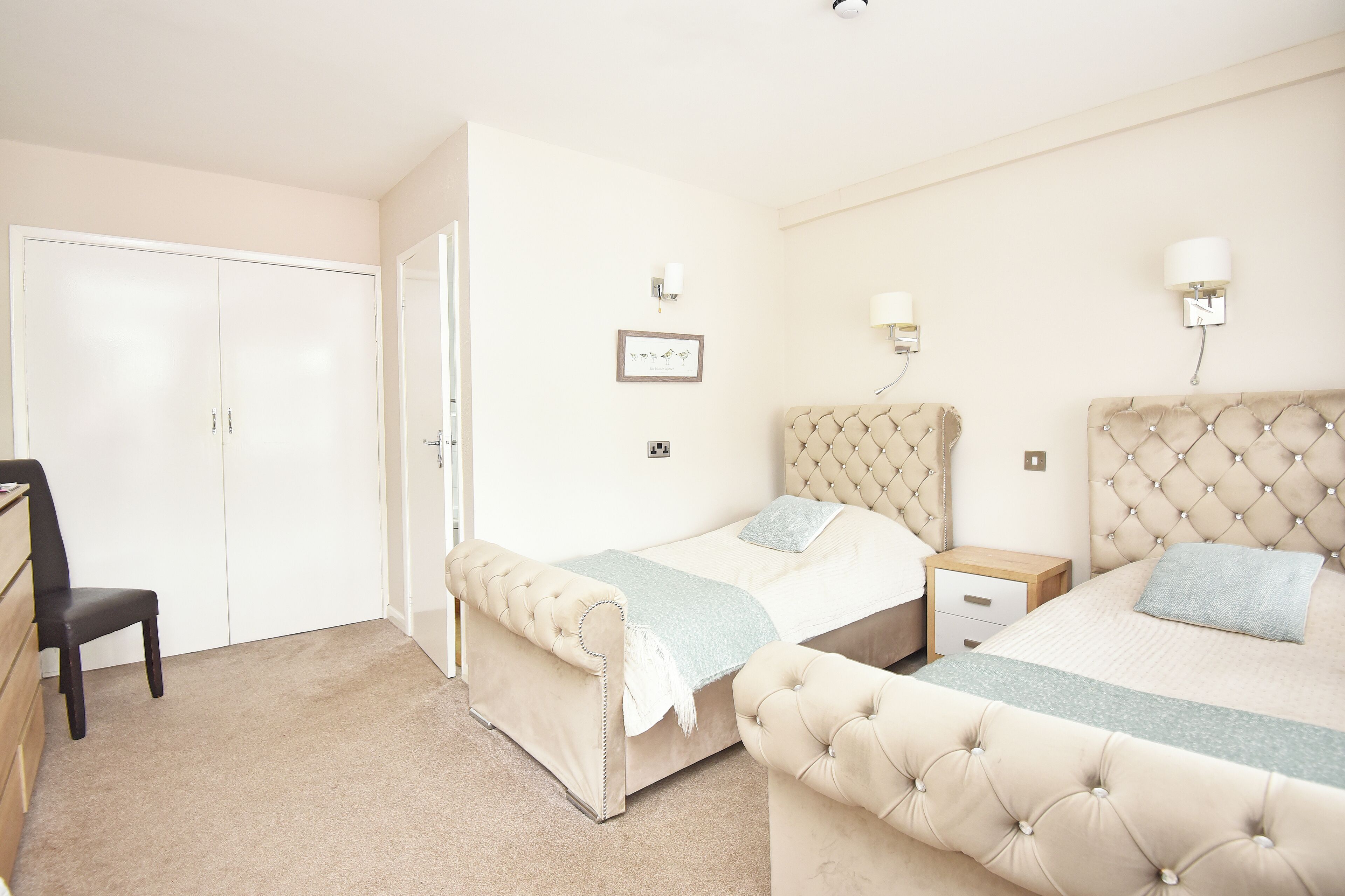A bedroom with two beds, a desk, and a chair.