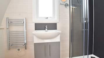 A bathroom with a white sink, a towel rack, and a glass shower enclosure.