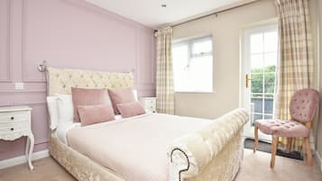 A bedroom with a large bed, a nightstand, a chair, and a window with curtains.