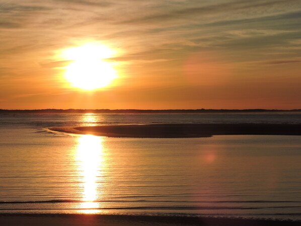 A sunset over a calm body of water with a visible shoreline.