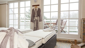 A hotel room with a bed, a window, a wooden chair outside, and a tiled floor.