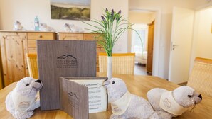 A wooden table with a welcome booklet, a plush toy, and a vase with flowers.