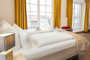 Un dormitorio con dos camas, cabeceros de madera, una mesita de noche con lámpara y cortinas amarillas.