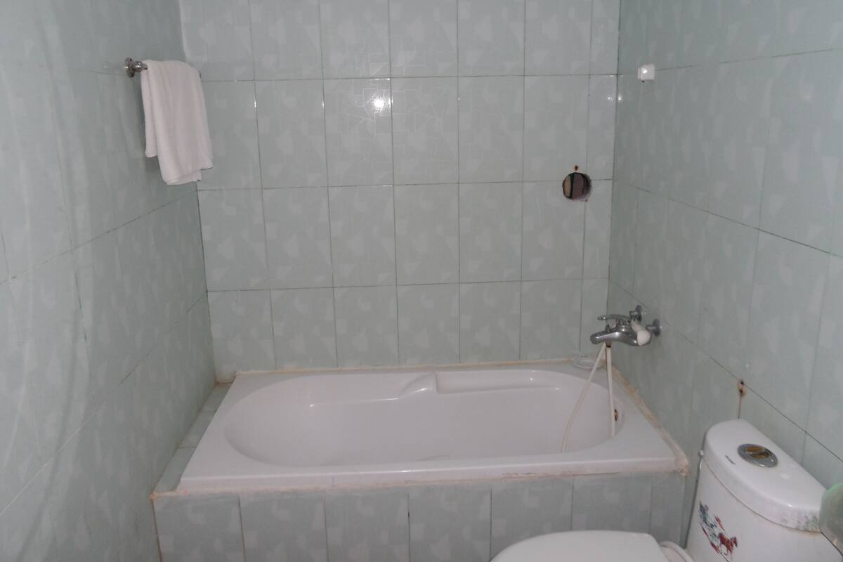 A bathroom with a bathtub, toilet, and a towel hanging on the wall.