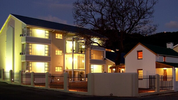 A multi-story building with illuminated windows and a gated entrance. - The Russel Hotel (Knysna)