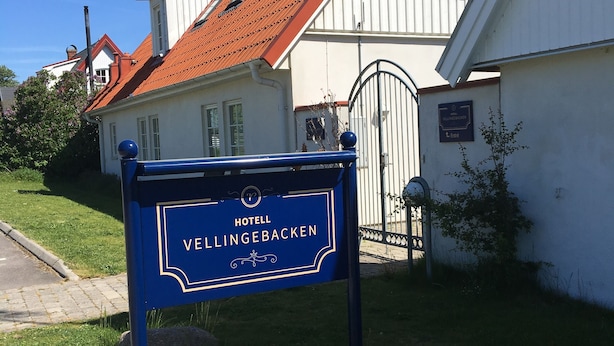 Un cartel para el Hotel Vellingebakken, con techo de tejas rojas y paredes blancas.