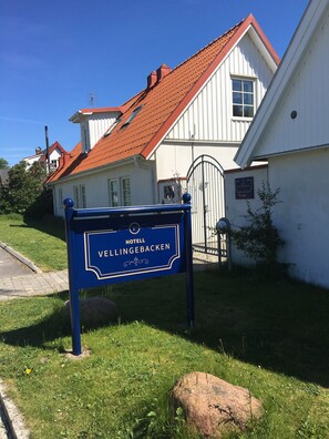 A sign for Hotel Vellingebakken with a red-tiled roof and white walls.