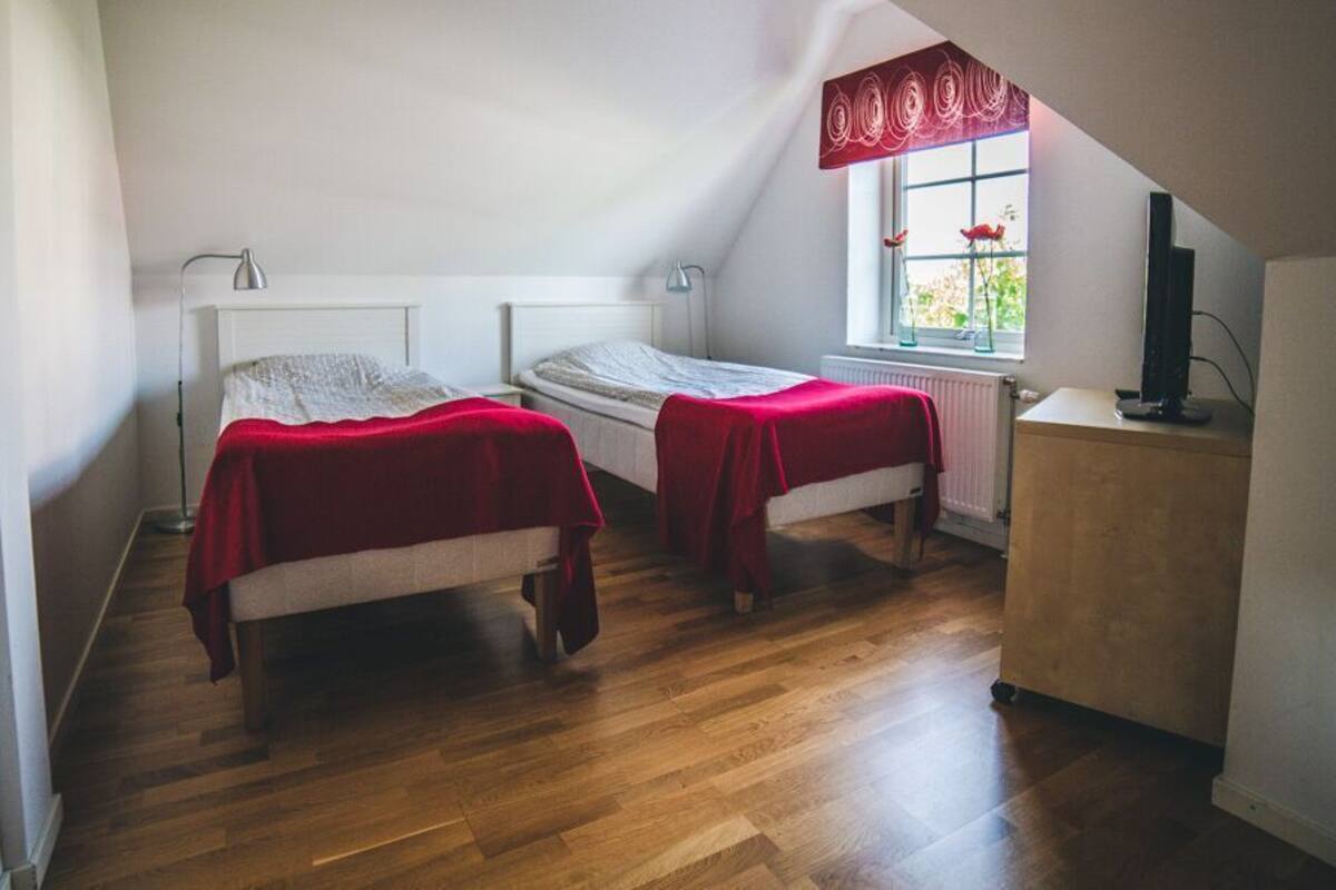 Ein kleines Zimmer mit zwei Betten, einem Schreibtisch und einer Heizung.