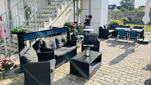 Un patio al aire libre con mobiliario de mimbre, una escalera y plantas en macetas.
