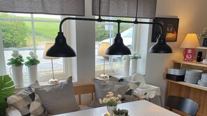 Comedor con una mesa dispuesta para cuatro personas, sillas negras, mantel a cuadros y un jarrón con flores.