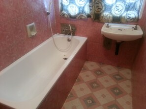 Bathroom features a bathtub, sink, and patterned wallpaper.