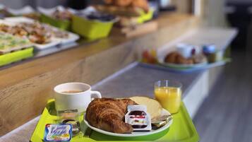 A breakfast buffet with various food items and beverages on trays.