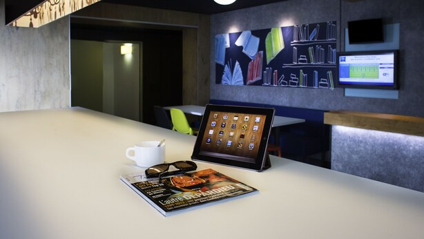 A modern conference room with a white table, a tablet, a magazine, and a cup. - ibis budget Chambéry Sud Challes les Eaux (Challes-les-Eaux)