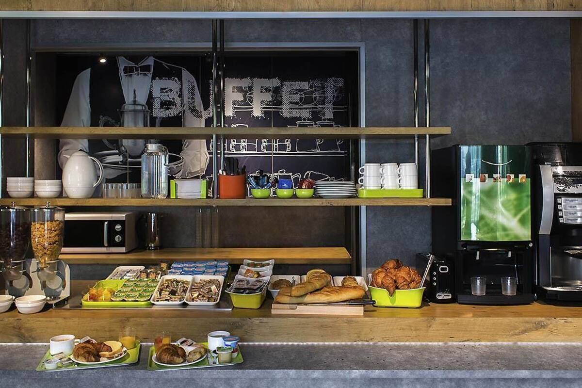 A breakfast buffet setup with various food items, a coffee machine, and a chalkboard with the word 'BUFFET' written on it.