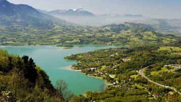 Een panoramisch uitzicht op een meer, omringd door weelderige groene heuvels en bergen.