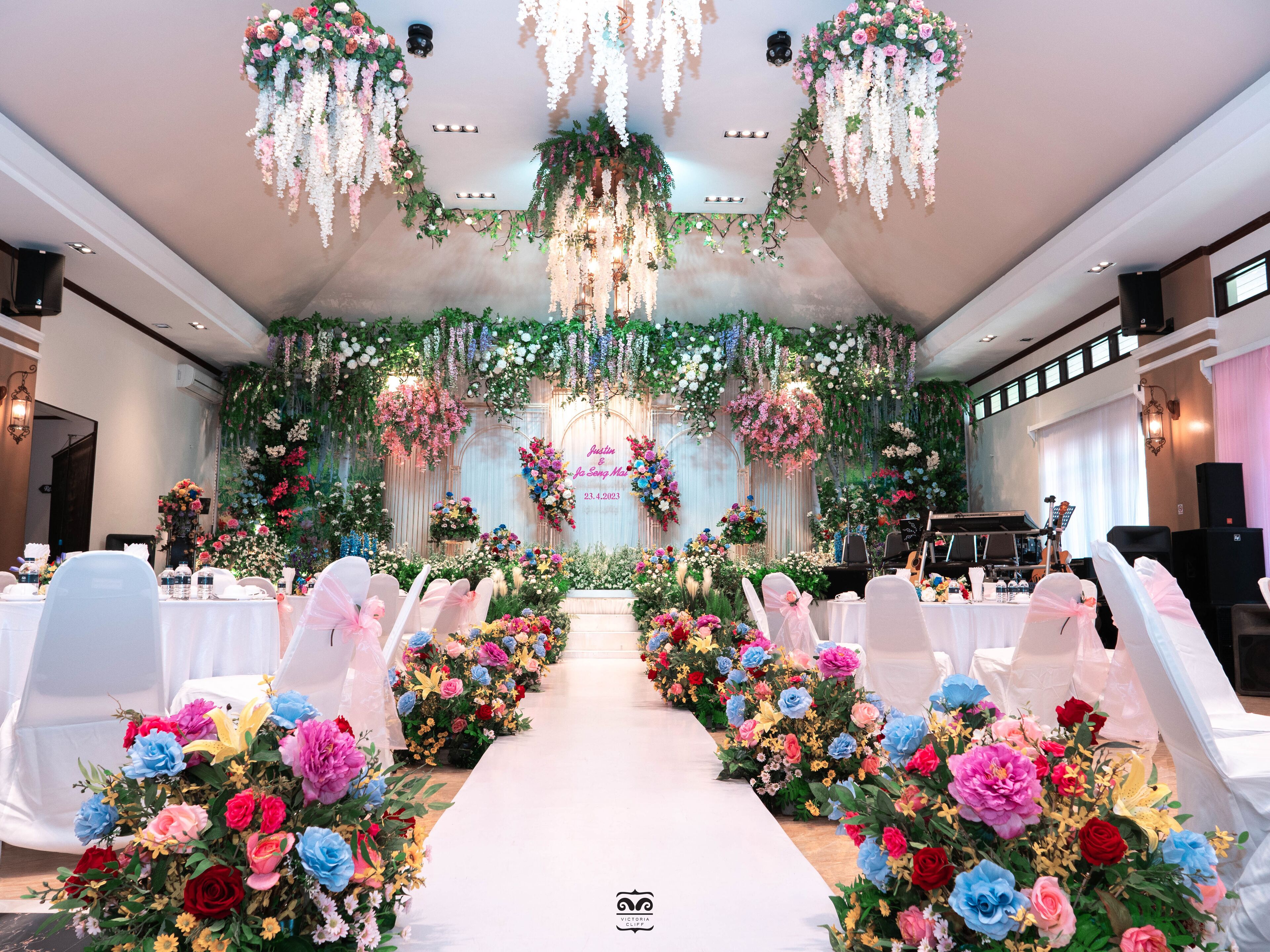 Eine Hochzeitslocation mit weißem Gang, floralen Dekorationen und einer Bühne mit Klavier.