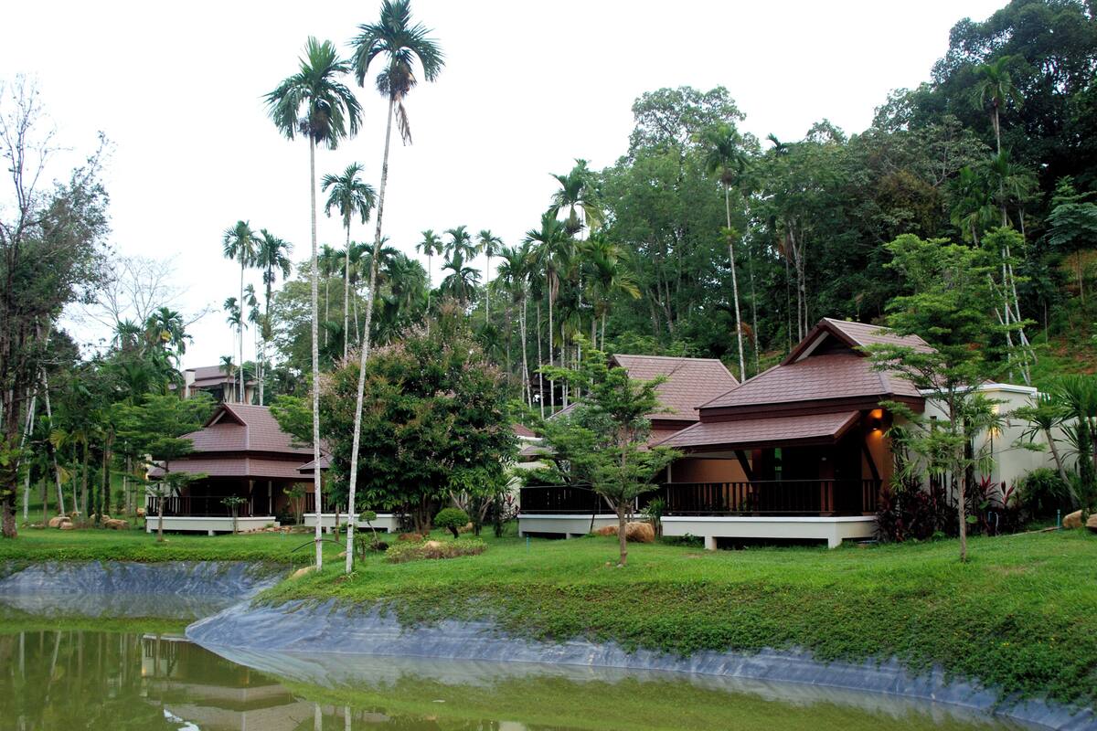 A resort with multiple buildings surrounded by lush greenery and a pond.